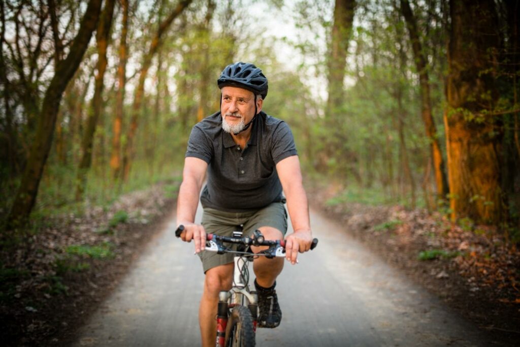 Mężczyzna w kasku rowerowym jedzie na rowerze po leśnej ścieżce