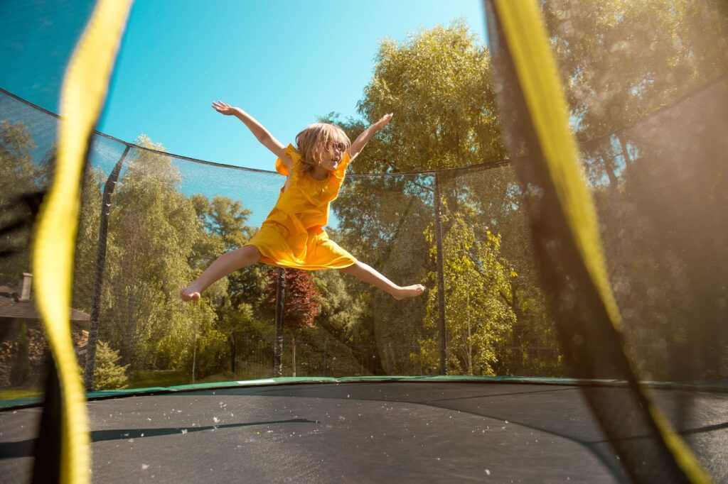 Dziewczynka skacze na trampolinie ogrodowej na świeżym powietrzu