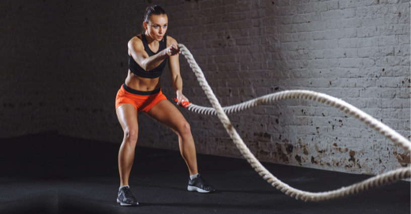 Kobieta trenuje z linami battle rope w siłowni 