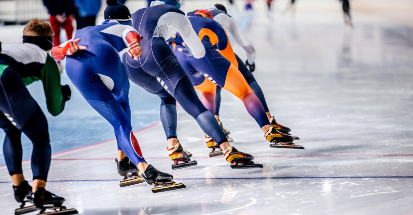 Grupa sportowców ściga się na lodzie w ubraniach do łyżwiarstwa szybkiego