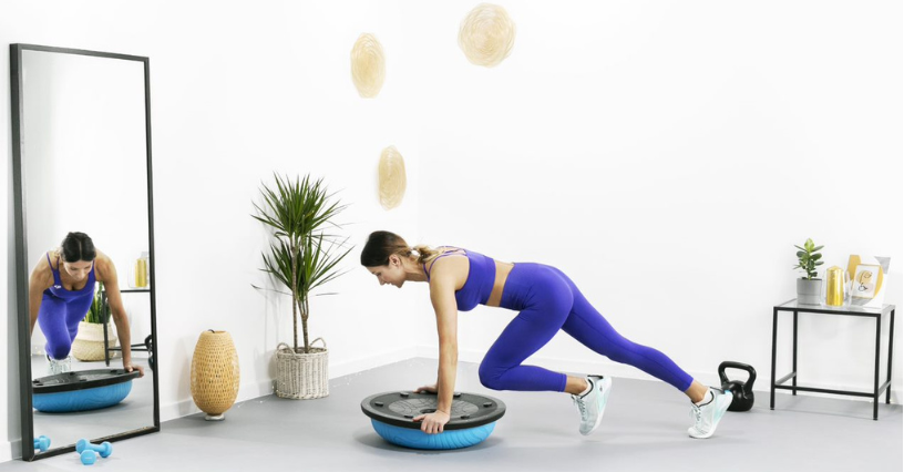 Kobieta w stroju sportowym trenuje brzuch na bosu w domu