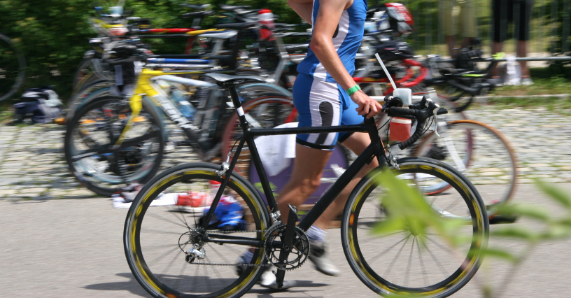 Mężczyzna w strój sportowy prowadzi rower podczas zawodów triathlonowych