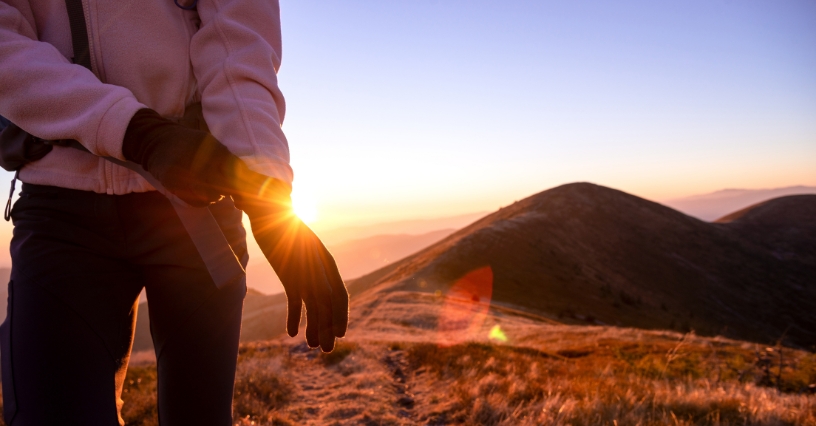Kobieta zakładająca rękawiczkę trekkingową w czasie górskiej wyprawy