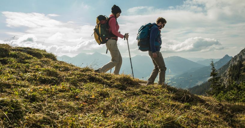 Pra turystów w odzieży trekkingowej i z plecakami wędruje górskim szlakiem