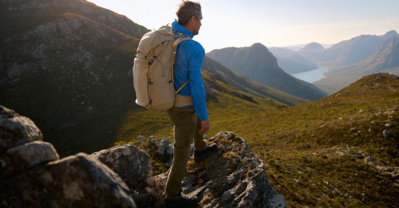 Mężczyzna z plecakiem trekkingowym oraz w odzieży outdoorowej Fjällräven podziwia górskie widoki